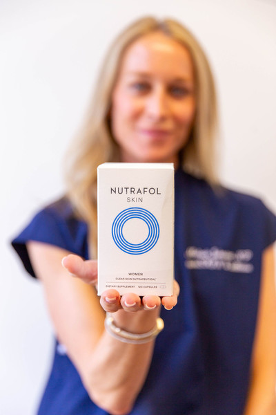 Nutrafol skin balance supplements held by nurse practitioner hand